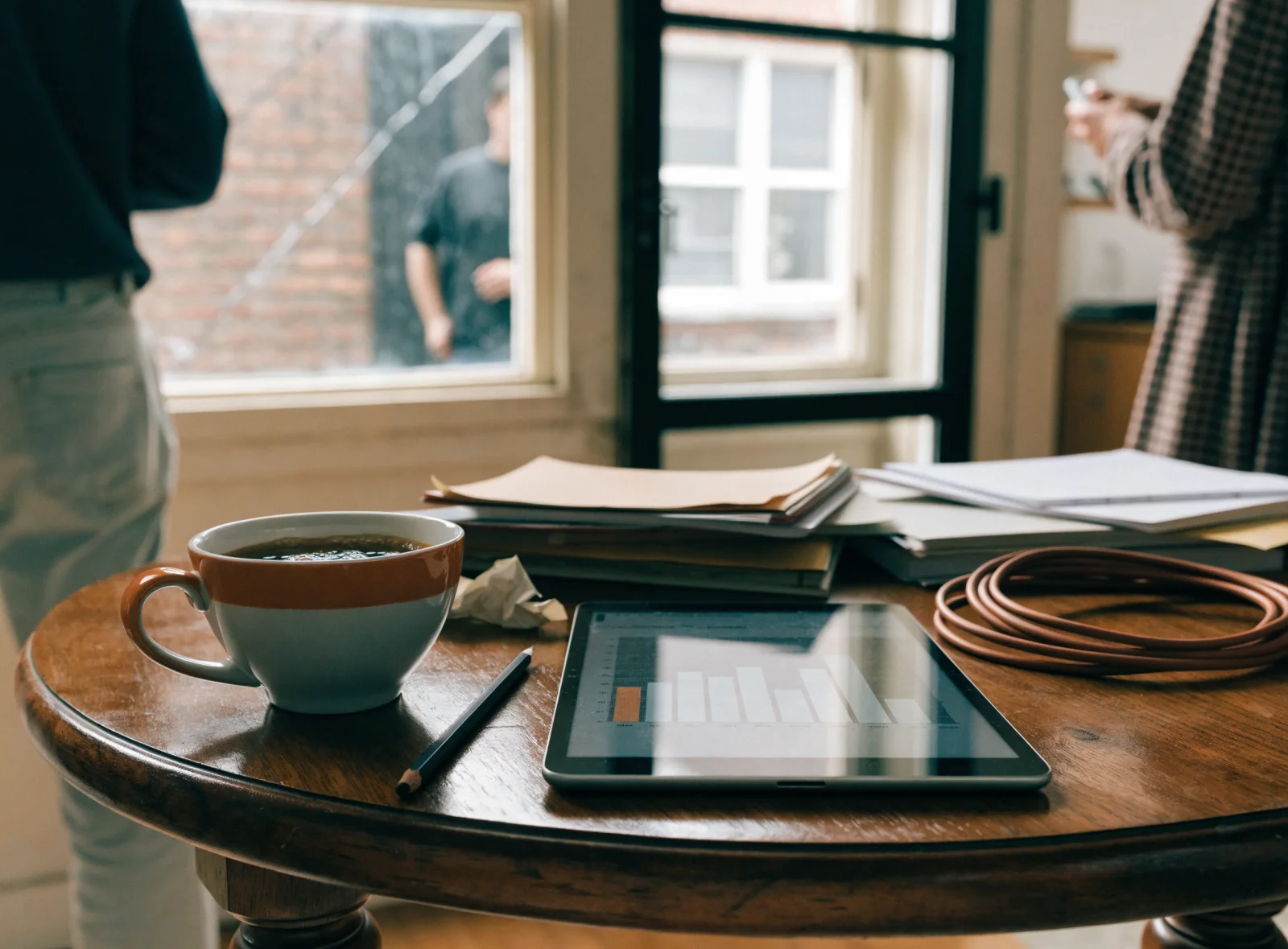 A tablet on a workshop bench showing a bar chart beside a coffee cup